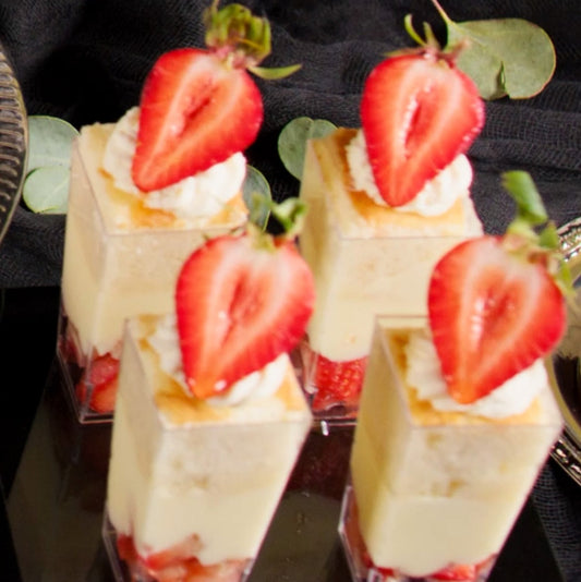 Small dessert cups with strawberry slices on a black surface