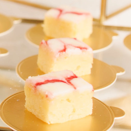 Three pieces of cake with a red swirl on a decorative yellow plate.